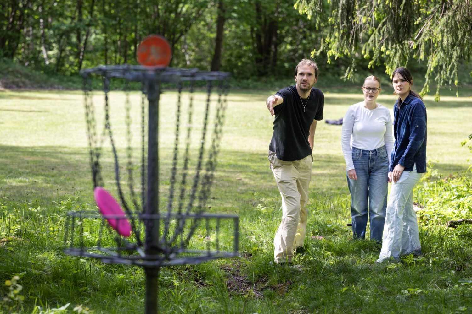 Tre spelar discgolf