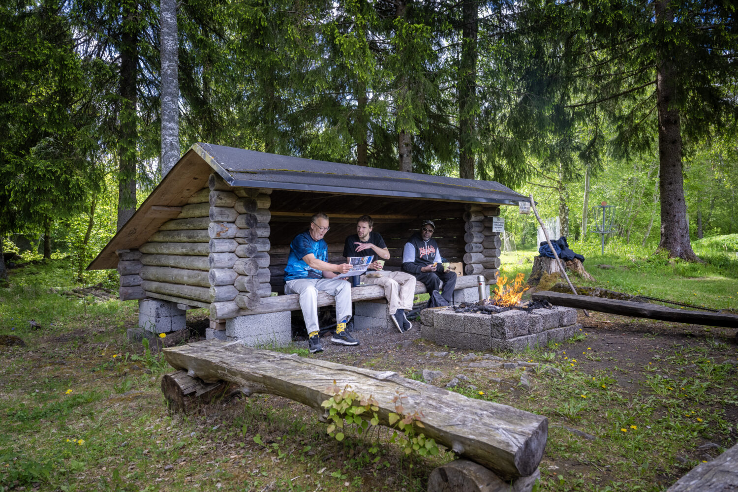 Tre män i vindskyddet vid öppen eld