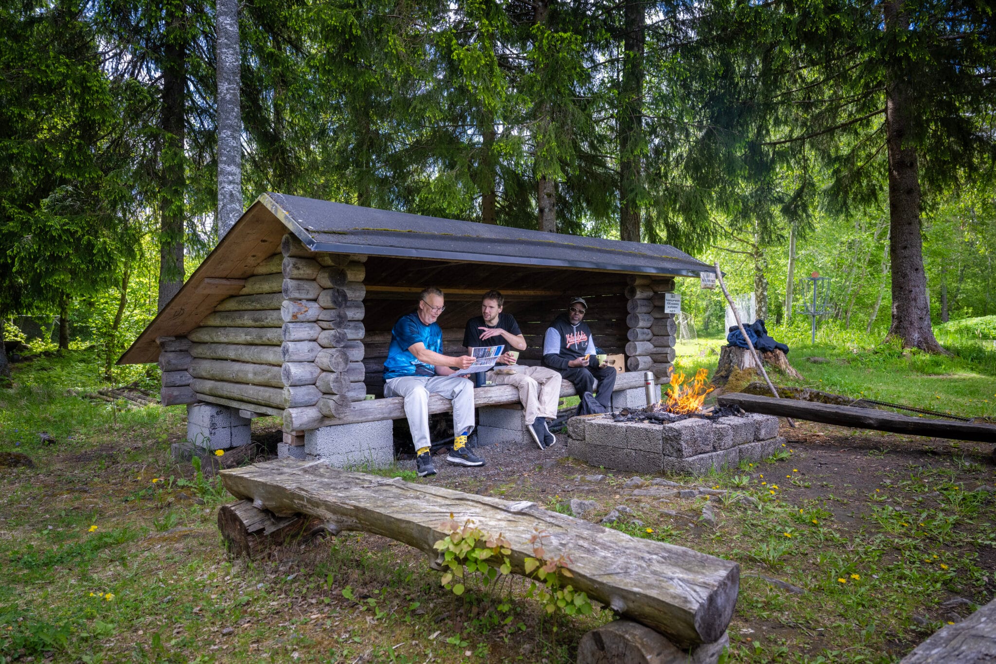 Tre män i vindskyddet vid öppen eld